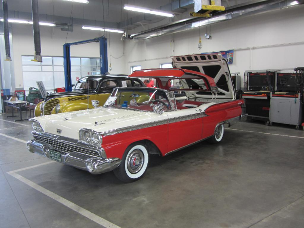 Fahrzeuge sind im Bild zu sehen, mit einem Tisch, Stühlen und verschiedenen Gegenständen links.