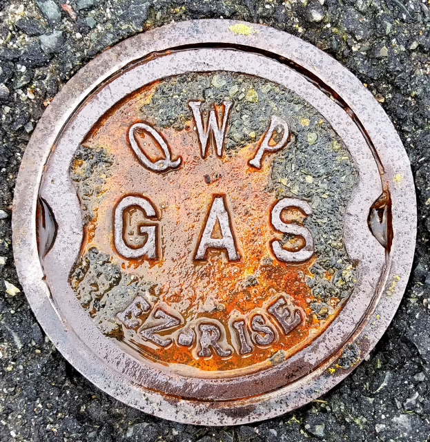 Eine Metallschachttreppe auf dem Boden mit der Aufschrift "QWP Gas".