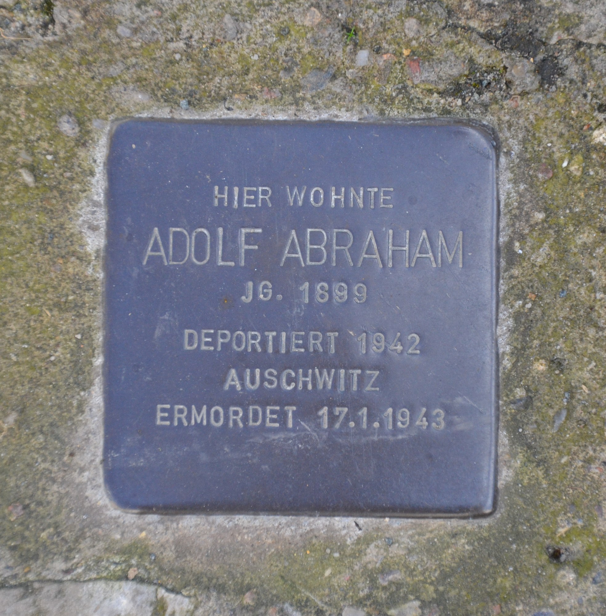 Rechteckige Plakette mit "Adolf Abraham" auf einer Steinwand.