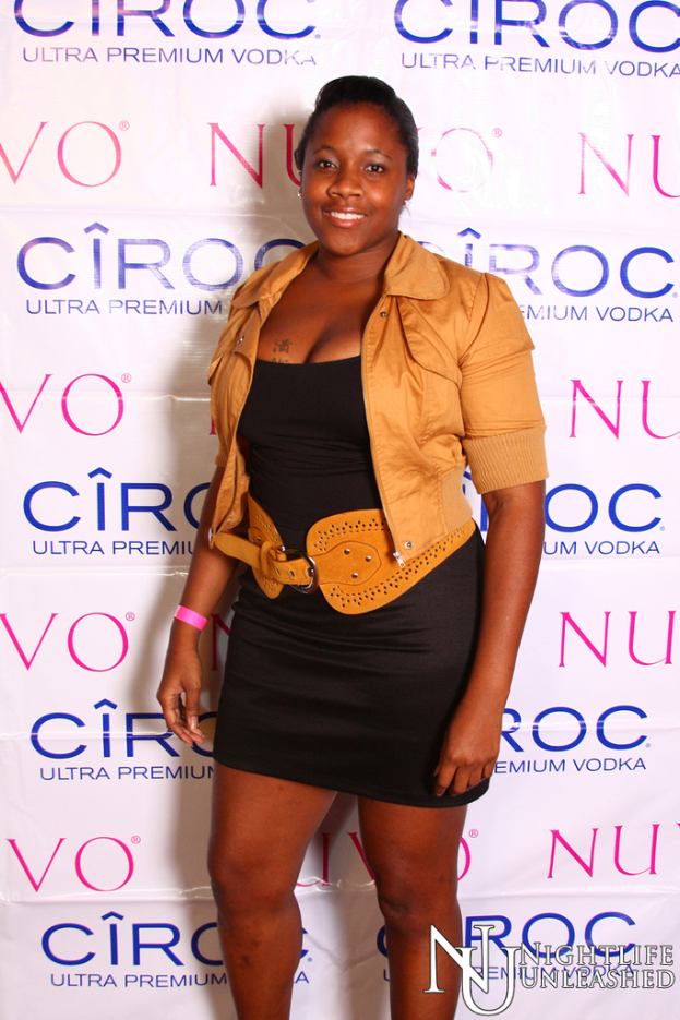 Eine Frau steht lächelnd vor einer Wand mit einem Sponsorennamen darauf.