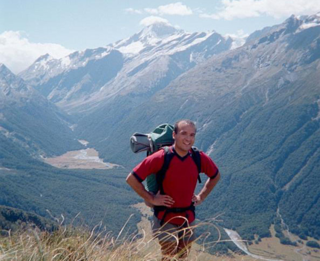 Eine Person mit einem Rucksack steht vor Bergen.