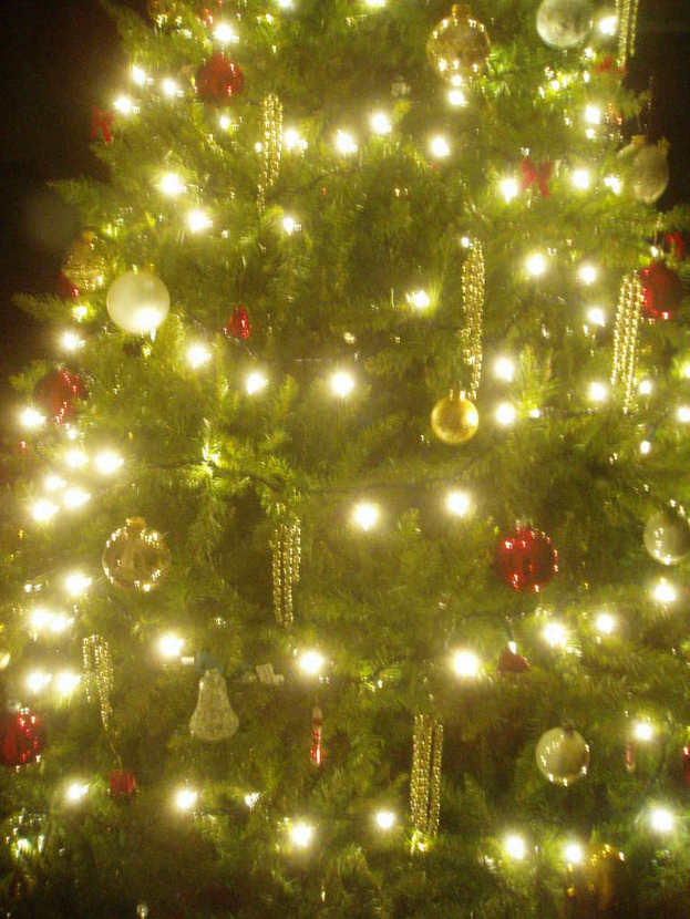 Ein mit Lichtern, Kugeln und verschiedenen Dekorationen geschmückter Weihnachtsbaum.