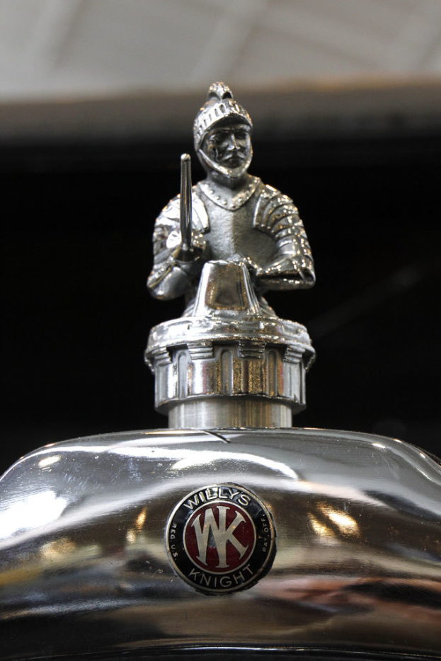 Eine Statue einer Person mit Helm und einem Gegenstand in der Hand, vor einer Logo.