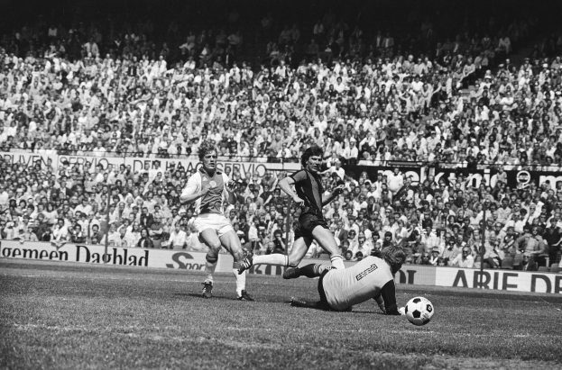 Schwarzes Foto von Männern, die Fußball auf einem Feld spielen, mit Zuschauern im Hintergrund und einem Banner mit der Aufschrift "Bundesliga 1978-79 Ajax 1-1 Hannover 96."