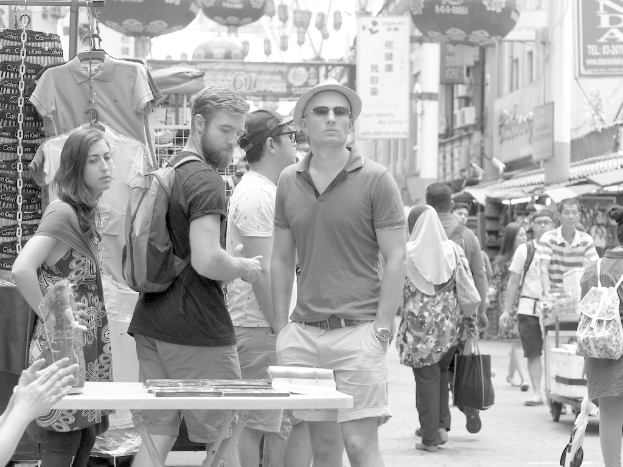 Ein belebter Marktplatz mit Ständen auf beiden Seiten und Plakaten in der Mitte.