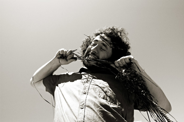 Ein Mann beißt in ein schwarz-weißes Audiokassettenband.