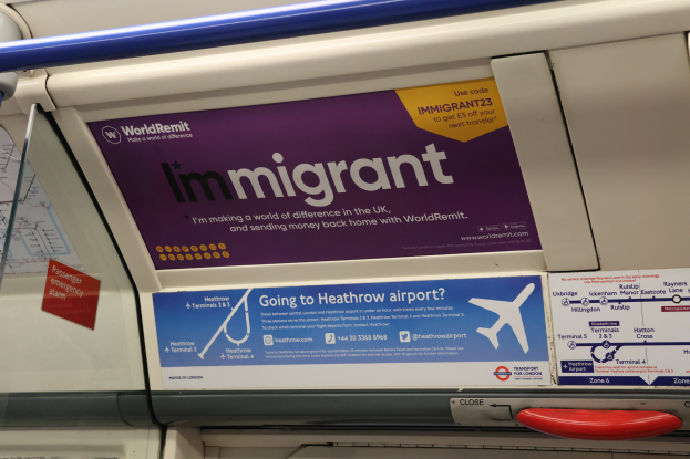 Ein Zug mit einer Seite, auf der 'Auslnder' steht, mit Plakaten an der Wand, einem Griff und einer Stange.