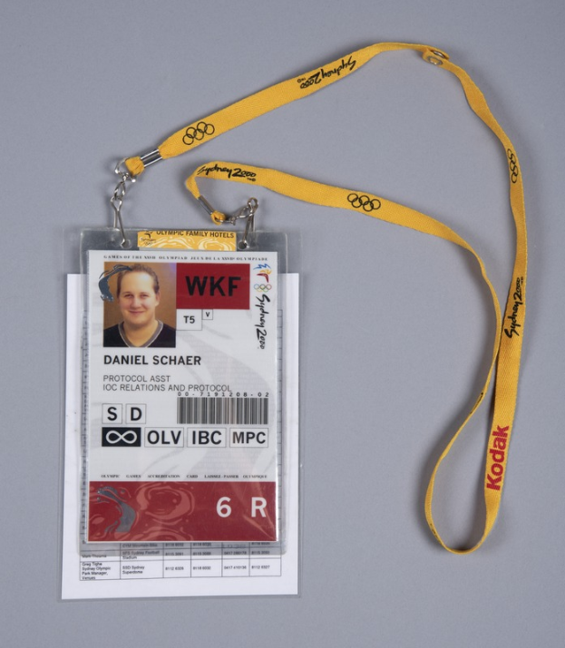 Ein Ausweis mit einem Foto und Text, an einem gelben Band befestigt, liegt auf einer Oberfläche.