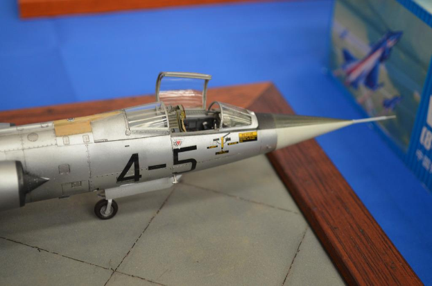 Ein Spielzeugflugzeug auf einer Platte, drei Objekte auf einer blauen Oberfläche und ein blaues Objekt mit Text und Bildern, das wie eine Platte aussieht.