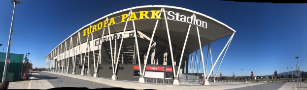 Großes mehrstöckiges Europa-Park-Stadion-Gebäude in Barcelona, Spanien, mit Text an seiner Fassade, umgeben von Pfählen, Lichtern, Bäumen und einem Zaun unter einem sichtbaren Himmel.