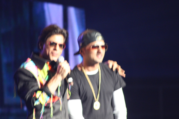 Zwei Männer in schwarzen Kleidern und Brillen stehen auf einer Bühne mit dunklem Hintergrund.