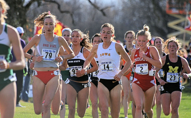 Eine Gruppe von Mädchen, die auf dem Boden laufen und alle Abzeichen auf ihren Kleidern tragen, mit Bäumen im Hintergrund.