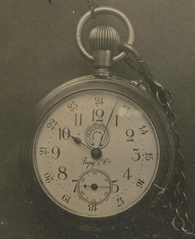 Altes Schwarz-Weiß-Foto einer Taschenuhr mit Kette, mit numeriertem Zifferblatt.