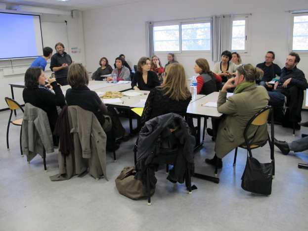 Eine Gruppe von Menschen, die sich unterhält und diskutiert, mit zwei Personen im Hintergrund, die miteinander sprechen