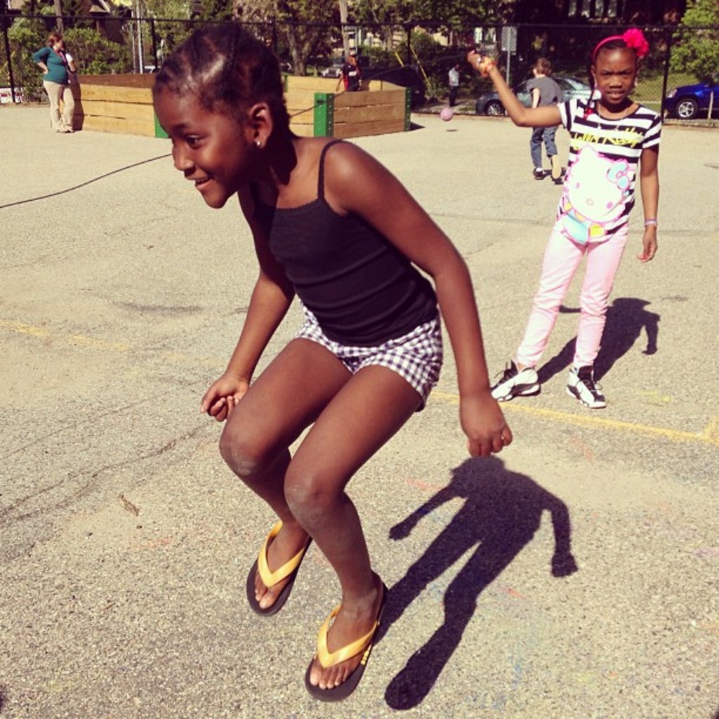 Ein spärlich besiedeltes Gebiet mit einem Zaun, verstreuten Bäumen und Autos im Hintergrund.