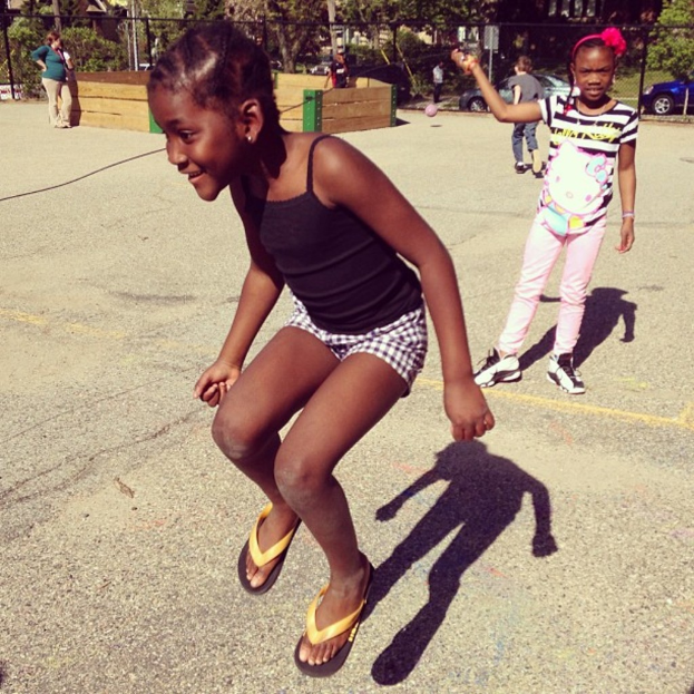 Ein spärlich besiedeltes Gebiet mit einem Zaun, verstreuten Bäumen und Autos im Hintergrund.