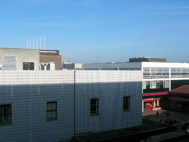 Eine Straßenansicht mit Gebäuden und Geschäften und einigen Menschen, die zwischen ihnen hindurchgehen.