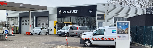 Ein Renault-Autohaus mit parkenden Autos vorne, umgeben von einem Metallzaun.