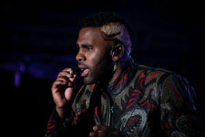 DJ Khaled trägt eine schwarze und rote Jacke und singt in ein Mikrofon auf der Bühne der Coachella Valley Music and Arts Festival 2018 in Indio, Kalifornien, vor einem dunklen Hintergrund.