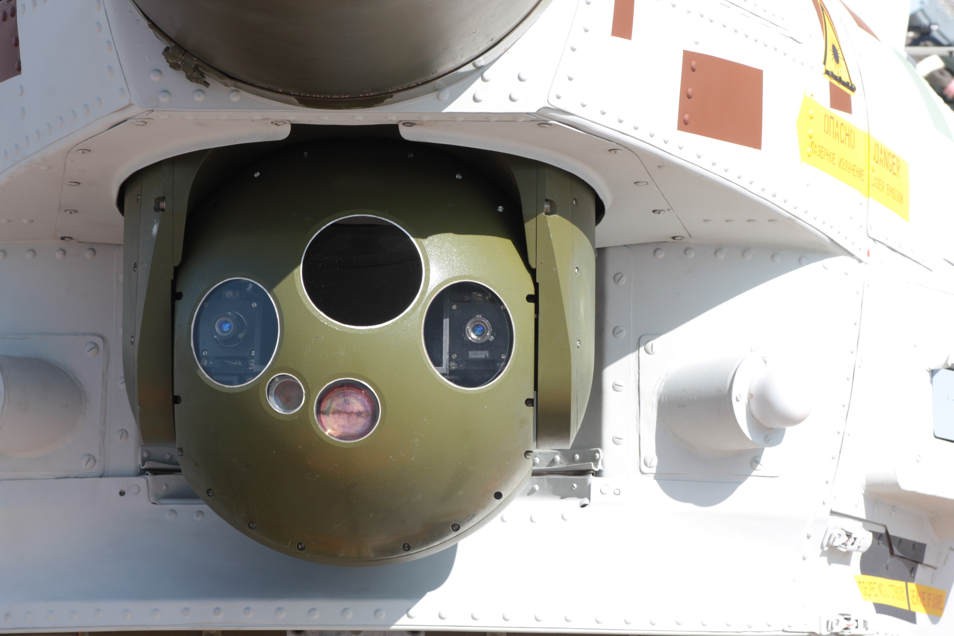 Nahaufnahme eines Militärfahrzeugs mit einer runden, grün-weißen Rakete, die seitlich in einem Metallrahmen montiert ist.