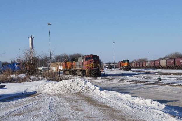Ein Zugmaschine vorne mit einem Zugdrehgestell auf der rechten Seite, auf Schienen geparkt mit Schnee auf dem Boden, trockenen Bäumen und einem Strommast im Hintergrund.