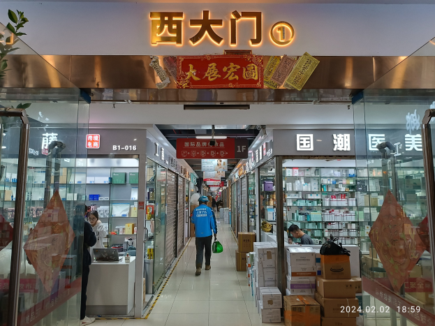 Innenansicht einer chinesischen Apotheke mit Glaswänden, Regalen voller Artikel, verstreuten Kartons, einer Pflanze auf der linken Seite und einem Namensschild oben, das besagt, dass es eine chinesische Drogerie ist.