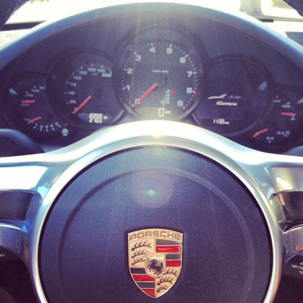 Ein Close-up-Blick auf das Armaturenbrett eines Porsche-Fahrzeugs mit Tacho und Lenkrad.