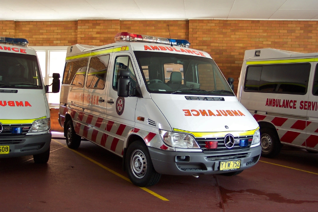 Ein Rettungswagen in Weiß ist vor einer Backsteinwand geparkt.