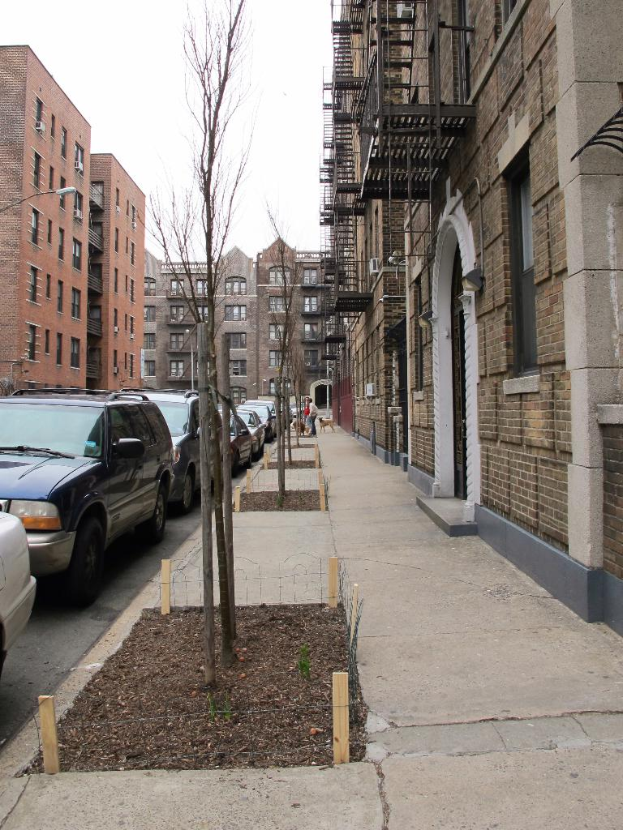 Eine spärlich bebaute Stadtlandschaft mit wenigen Autos und Gebäuden im rechten Eck, sowie einigen anderen Gebäuden im linken Eck.
