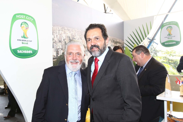 Eine Gruppe von Menschen, die mit einigen lÃ¤chelnden Menschen und einem FIFA-Weltmeisterschaftsplakat im Hintergrund steht.