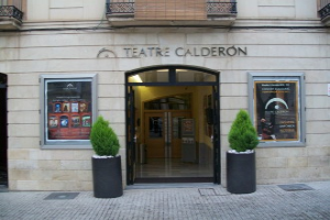 Das Theater Calderón in Madrid, Spanien, ein Gebäude mit Fenstern, Türen, Geländern und Text an der Wand, mit Zimmerpflanzen im Vordergrund.