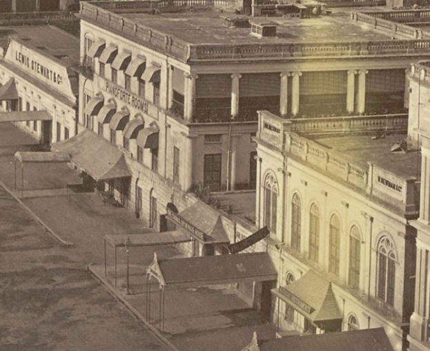 Altes Schwarz-Wei├č-Foto einer Stadtstra├če mit Geb├Ąuden, Fenstern, S├Ąulen, Namensschildern, Hütten und Masten.