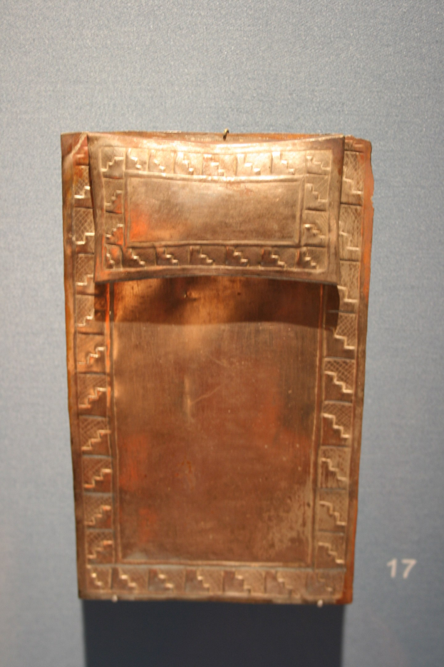 Kupferplatte mit detaillierten Entwürfen in einem Museum ausgestellt, mit einer Wand und einer Zahl im Hintergrund.