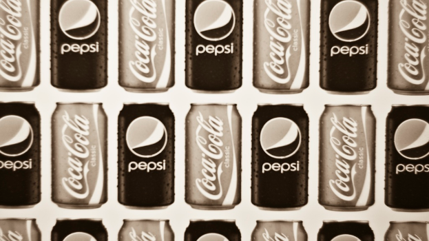 Zwei Dosen Soda, eine Pepsi und eine Coca-Cola, sind nebeneinander angeordnet.