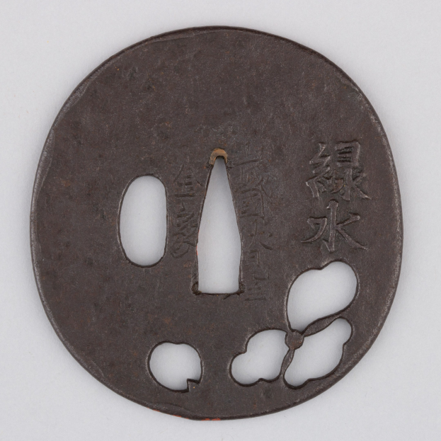 Ein rundes japanisches Tsuba mit floralem Design und eingravierter Schrift, vor einem weißen Hintergrund dargestellt.
