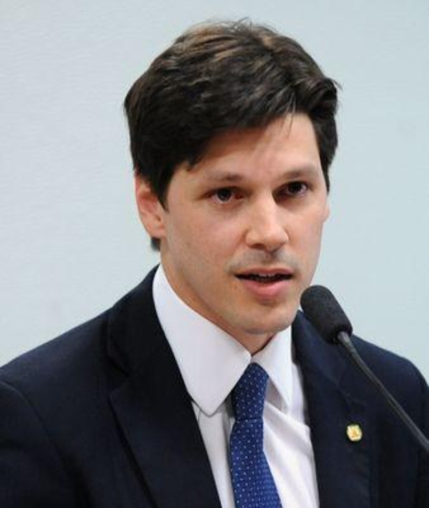 Ein Mann im Anzug und Krawatte spricht vor einer Wand in ein Mikrofon, wahrscheinlich zur Genehmigung eines Gesetzesentwurfs durch die Regierung.