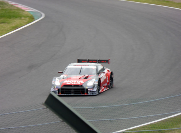 Ein Nissan GT-R Nismo GT3 Rennauto auf der Nürburgring 24 Stunden Strecke, mit grünem Gras auf beiden Seiten der Strecke.