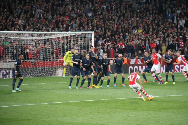 Fußballspieler auf dem Feld mit einer großen Menge im Hintergrund.