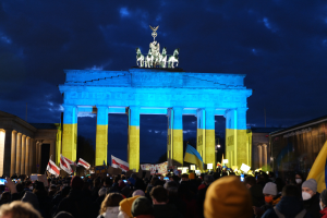Eine Menschenmenge steht vor dem Brandenburger Tor in Berlin, Deutschland, mit Fahnen und Plakaten in den Händen, auf der rechten Seite eine Fahne.