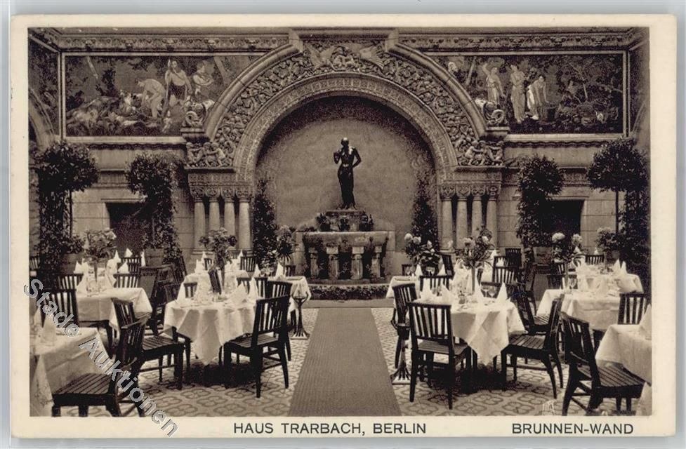 Ein altes Schwarz-Weiß-Foto eines Berliner Restaurants mit Tischen, Stühlen, Blumenvasen, einer Statue, Skulpturen und Pflanzen an den Wänden, mit Text unten.