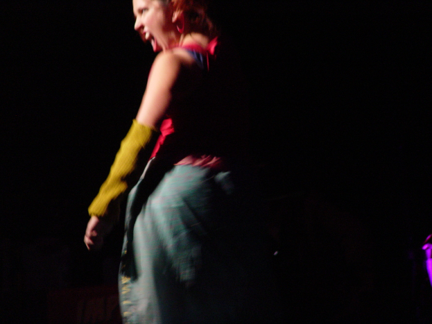 Eine Person steht mit offenem Mund, scheinbar schreiend, vor einem dunklen Hintergrund.