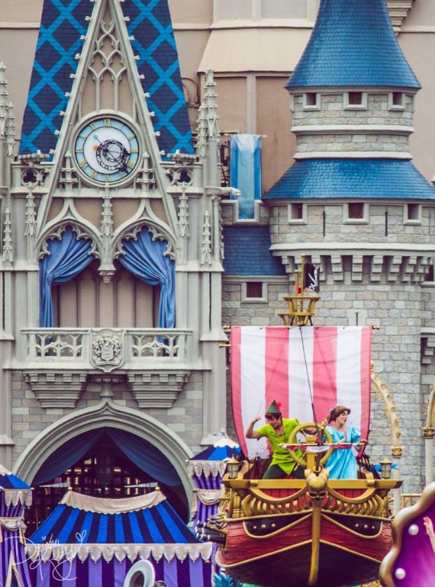 Eine bootähnliche Struktur auf der rechten Seite mit tanzenden Menschen und einer Flagge, mit einem Gebäude im Hintergrund, das eine Uhr und Vorhänge zeigt.