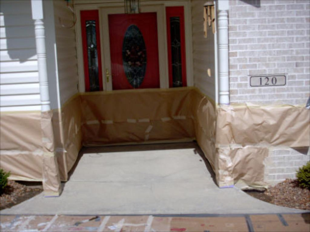 Ein Gebäude mit einer Tür und Fenstern in der Mitte, ein Schild mit der Aufschrift "120" rechts daneben und Pflanzen an der unteren linken und rechten Ecke, mit Putz an der Wand am Boden.