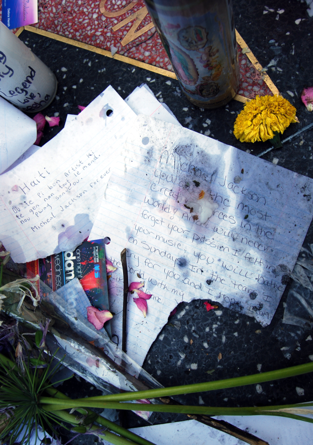 Ein Denkmal auf dem Hollywood Walk of Fame in Los Angeles, Kalifornien, mit einem Strauß bunter Blumen, Papieren, Büchern und einem Glas auf dem Boden.