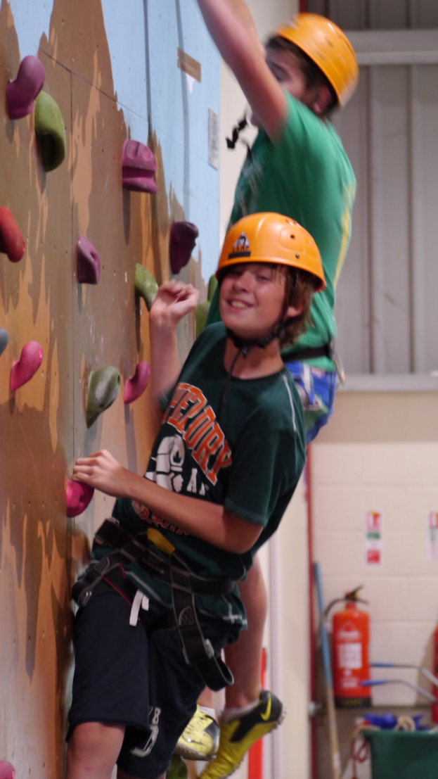 Eine Person klettert an einer Wand hoch, neben ihr befindet sich ein Feuerl√∂scher.