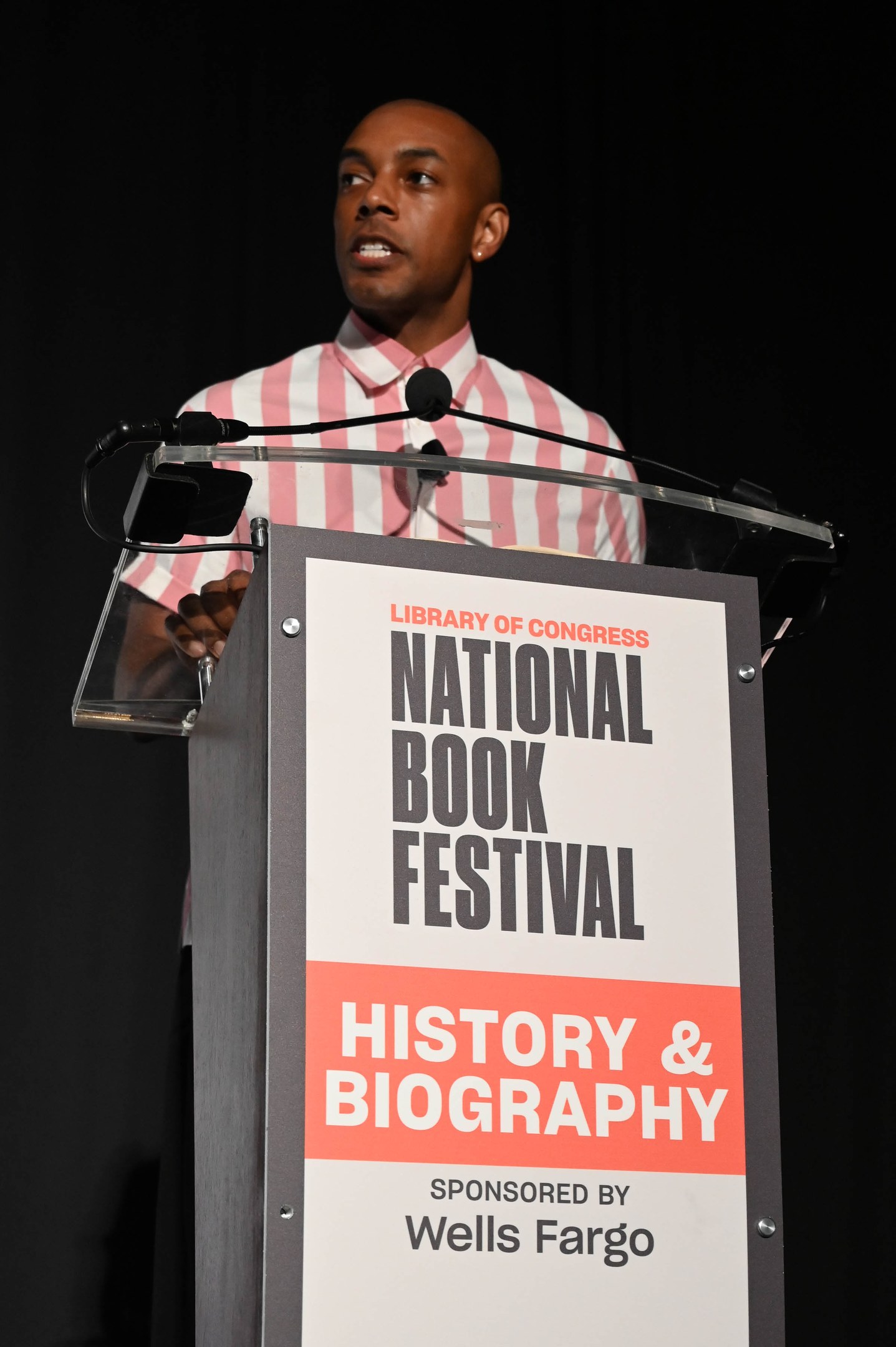 Ein Mann spricht an einem Podium mit einem Mikrofon vor einem Schild, auf dem "National Book Festival Geschichte & Biografie" steht.